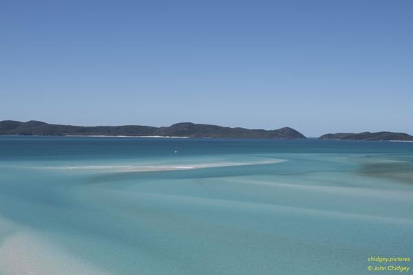 Passage Between Haslewood And Teague Islands: During a break in the COVID19 lockdowns and restricted to travel within our own state only, we trekked to the amazing Whitehaven Beach in the Whitsunday Islands in June, 2020. This photo is taken from above Hill Inlet looking over the bay towards the narrow passage between Haslewood Island and Teague Islands, South of Whitehaven Beach. The turquoise water and pure white sand is breathtaking and unforgettable.